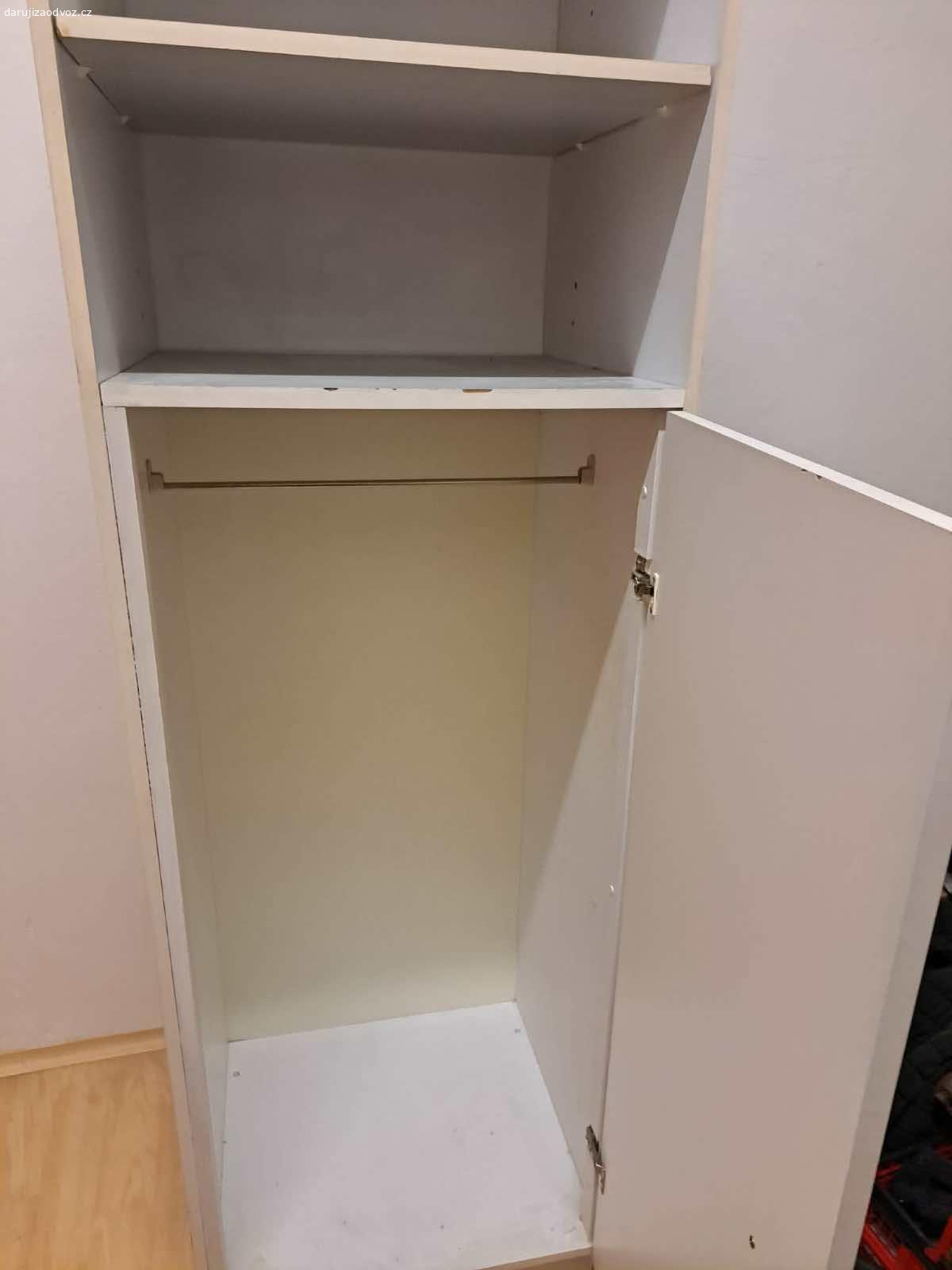 Bílá vysoká skříň. Skříň s dvěmi otevřenými poličkami a prostorem pro ramínka. 

s64 h58 v208