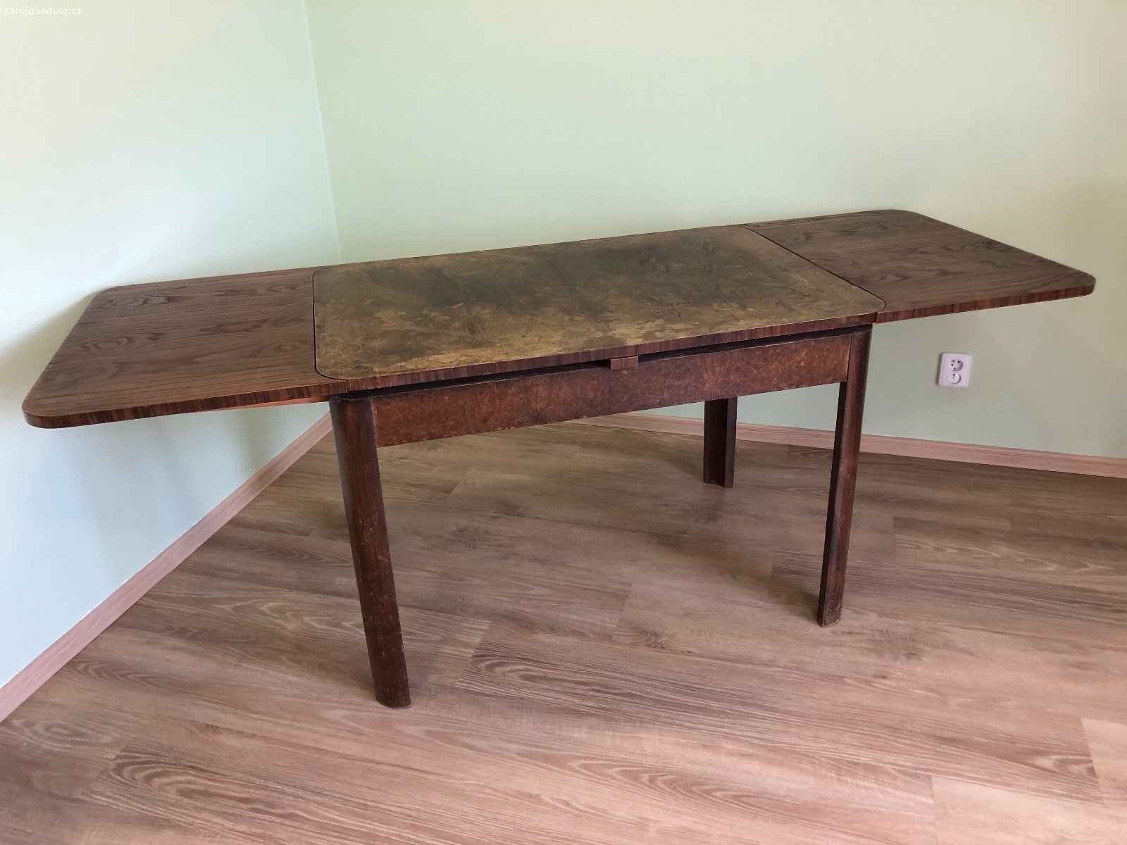 Daruji rodinný stůl. Daruji za odvoz letitý rozkládací stůl. Po zbroušení a napuštění olejem bude jako nový. Stůl má rozměry 110 x 75 cm ve složeném stavu. V rozloženém stavu měří na délku 205 cm. Ke stolu se vejde až 10 lidí. Pro transport lze desky stolu oddělat.