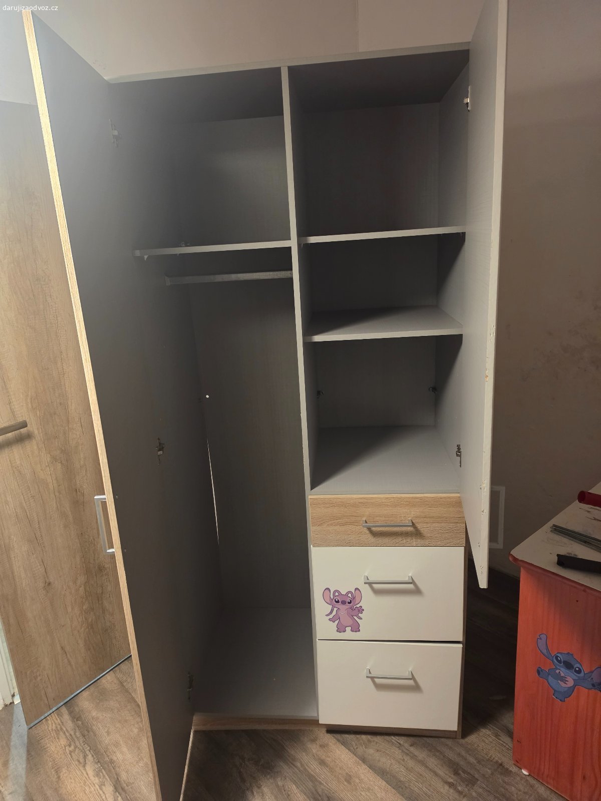 Daruji skříň - rezervováno. Daruji šatní skříň z dětského pokoje. Skříňi bohužel chybí k jednomu šuplíku dno (viz. foto) a spodní šuplík má rozbité kolejničky na vysouvání. Na skříni jsou samolepky, které se dají jednoduše odstranit.
Rozměry  Š 91 x V 197 x H 58