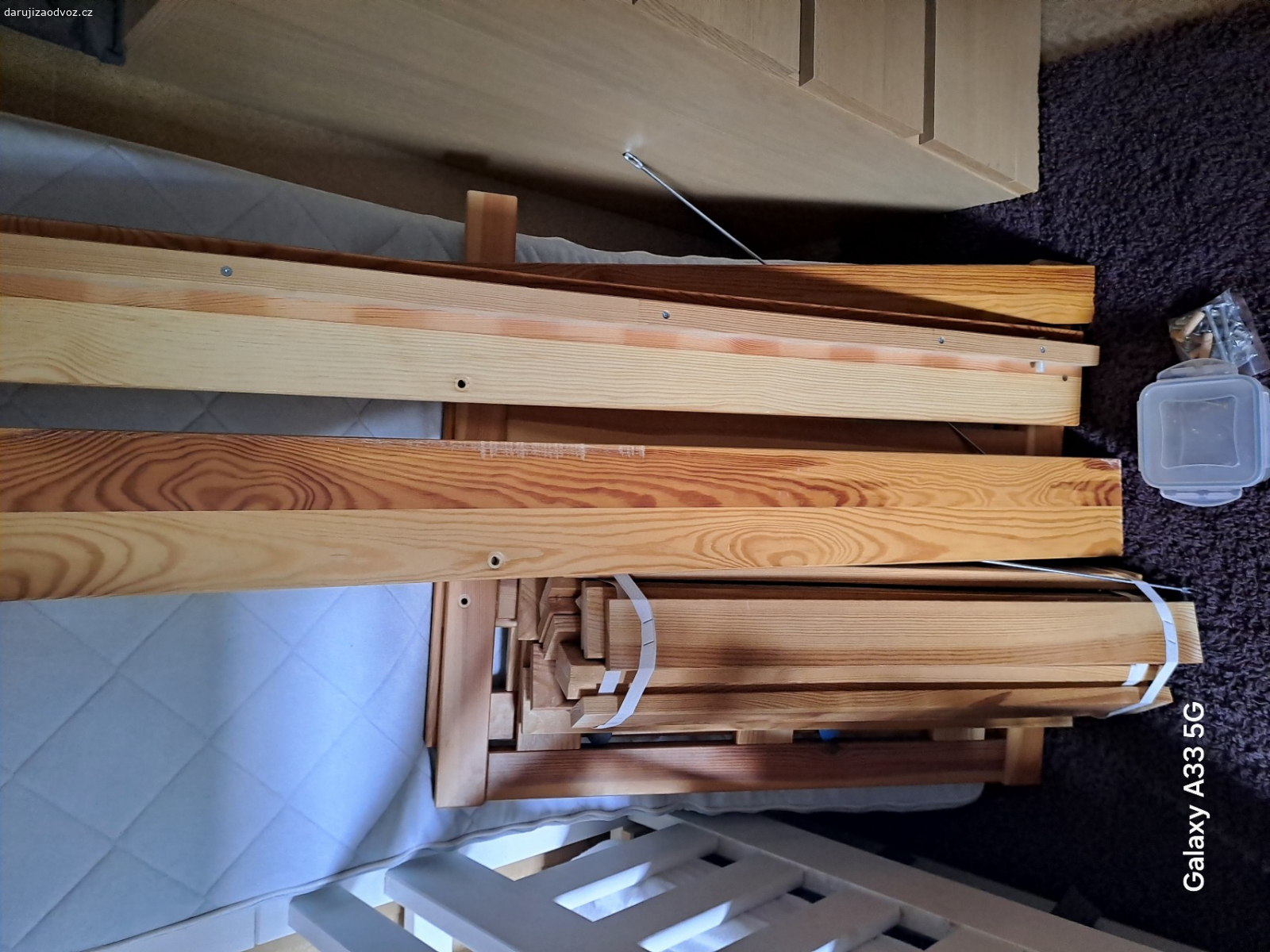 Dětská postel. U boční zábrany chybí šroub. Rýhy v bočnici.