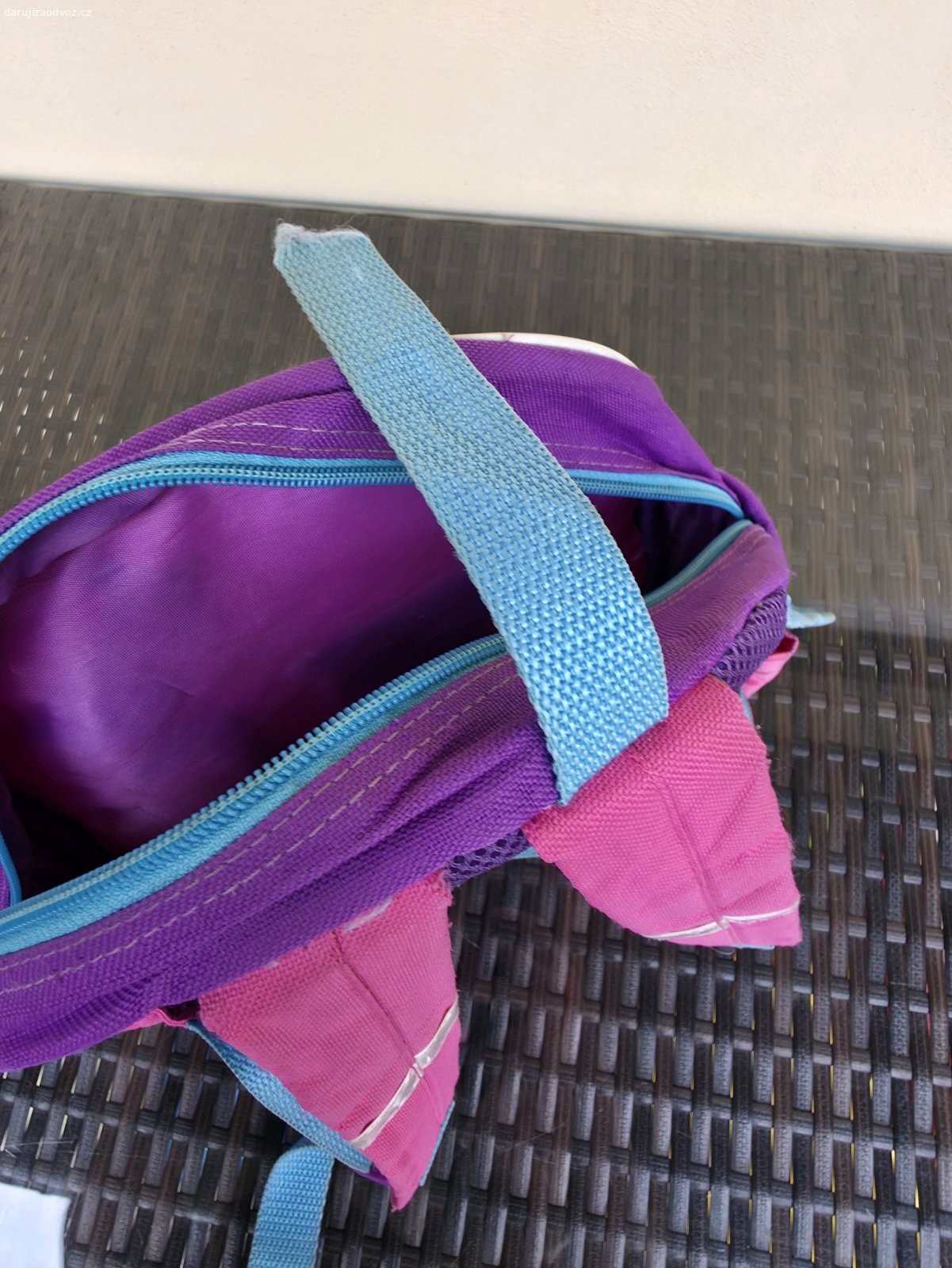 Dětský dívčí batoh. Batoh s 1 komorou na zip a 2 postranními kapsičkami na suchý zip. Reflexní prvky na ramenních popruzích, na zadním obrysu a postranních kapsičkách. Zachovalý, zip funkční, pouze utržené poutko (viz foto) a je třeba ho vyprat. Zhruba vysoký 28 cm, hluboký 9 cm, široký 33 cm.