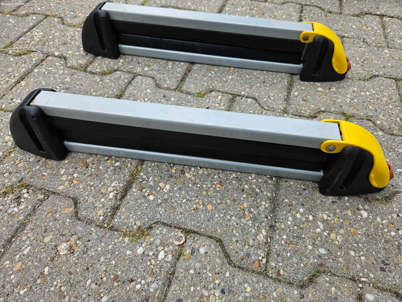 Držák lyží / snowboardů na střešní nosič. Celková délka je 53 cm, vnitřní délka pro uložení lyží / snowboardů je 37 cm.