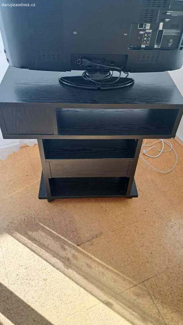TV stolek. Daruji zajímavě řešený TV stolek s několika patry v tmavém provedení s podstavcem na 4 kolečkách a se šuplíkem. Rozměry š 40cm, d 80cm,výška 70cm. Vlastní odvoz.